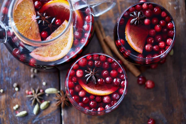 Elevated view of homemade mulled wine with cranberries, cinnamon sticks and oranges on tabletop in kitchen — Stock Photo