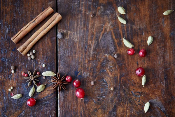 Vista superior de arándanos dispersos, palitos de canela y clavel en la mesa de madera en la cocina - foto de stock