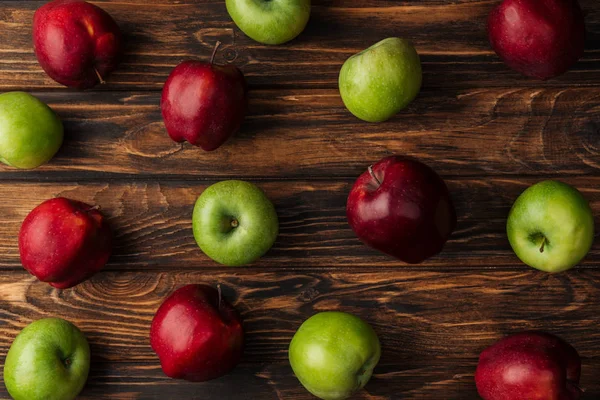 Vista superior de manzanas rojas y verdes maduras sobre mesa de madera - foto de stock