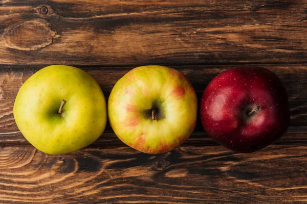 Draufsicht auf eine Reihe reifer bunter Äpfel auf einem Holztisch — Stockfoto