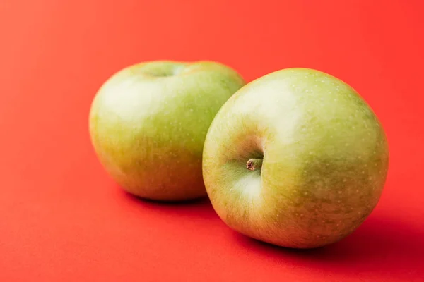 Grosses pommes vertes mûres sur fond rouge — Photo de stock