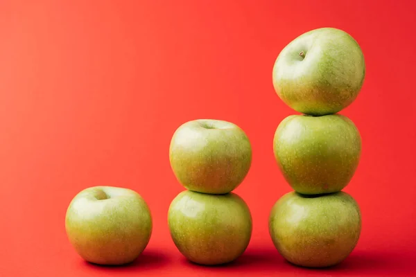 Pilas de manzanas verdes maduras sobre fondo rojo - foto de stock