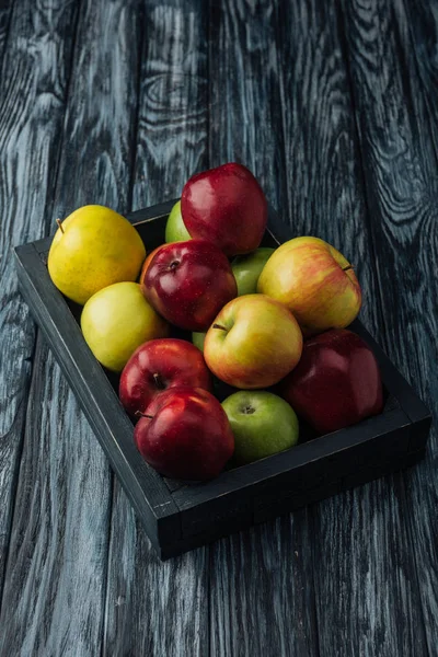Wooden box with ripe red, green and golden apples on table — Stock Photo