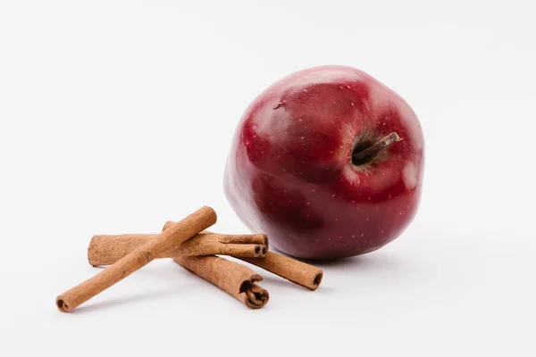 Großer roter köstlicher Apfel und Zimt auf weißem Hintergrund — Stockfoto