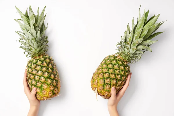 Cropped view of woman holding pineapples in hands on white background — Stock Photo