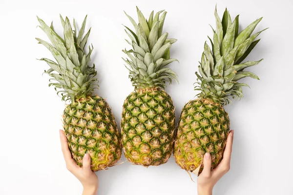 Cropped view of woman holding delicious pineapples in hands on white background — Stock Photo