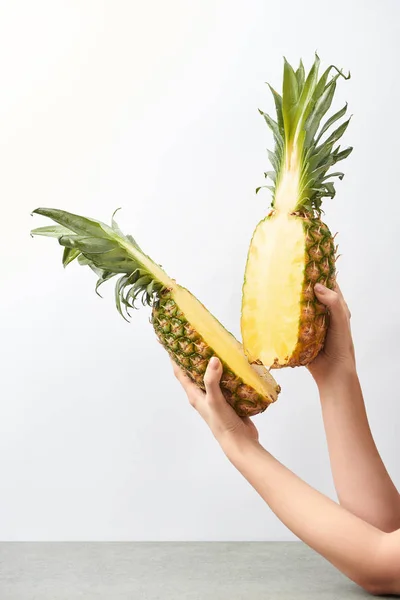 Cropped view of woman holding yellow pineapple halves in hands isolated on white — Stock Photo