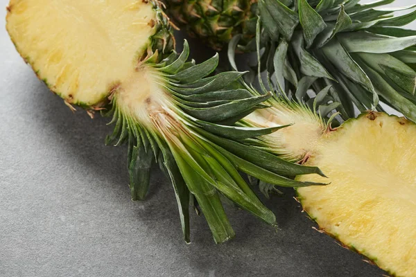 Moitiés d'ananas jaune mûr sur fond gris — Photo de stock