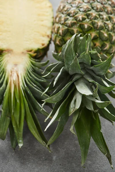 Semi maturi e ananas interi su fondo grigio — Foto stock