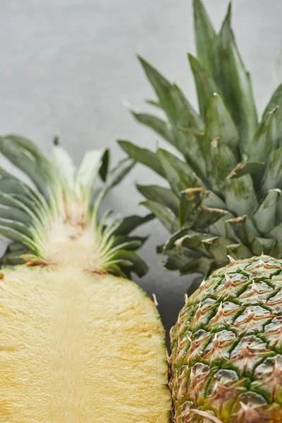 Mise au point sélective de l'ananas entier et de la moitié sur fond gris — Photo de stock
