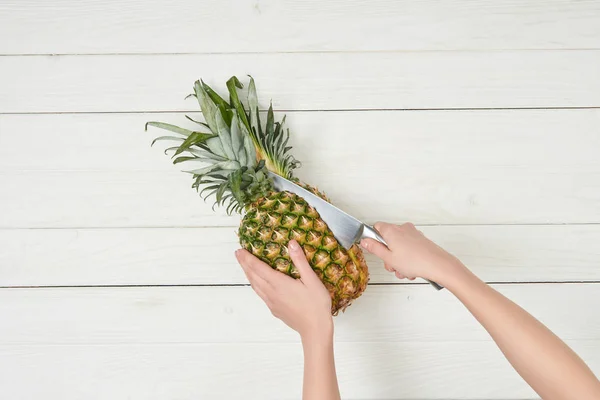 Cropped view of woman cutting organic pineapple with knife — Stock Photo