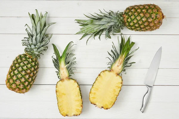 Top view of ripe halves near whole pineapples — Stock Photo