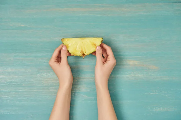 Cropped view of woman holding yellow slice of pineapple in hands — Stock Photo