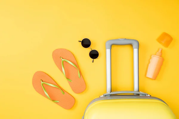 Vista superior del equipaje, gafas de sol y chanclas sobre fondo amarillo - foto de stock