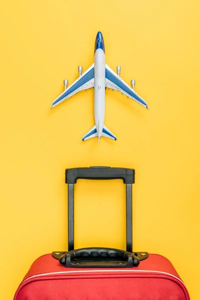 Vista superior del equipaje rojo y del avión de juguete sobre fondo amarillo - foto de stock