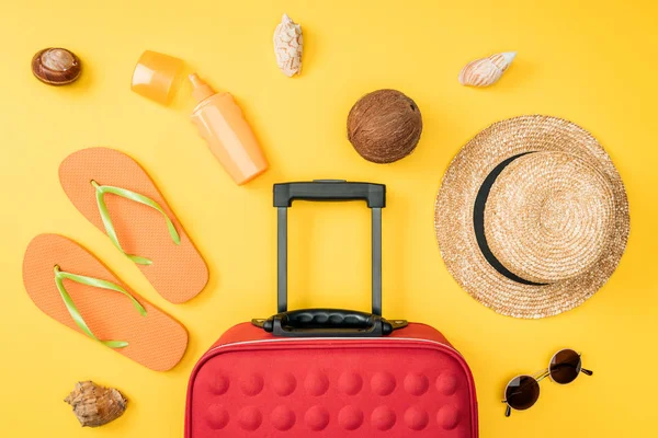 Vista dall'alto di cappello di paglia, occhiali da sole, cocco, infradito, borsa da viaggio e conchiglie su sfondo giallo — Foto stock