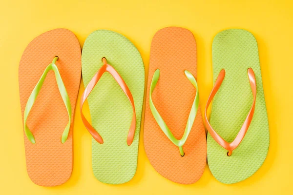 Draufsicht auf bunte Flip-Flops auf gelbem Hintergrund — Stockfoto