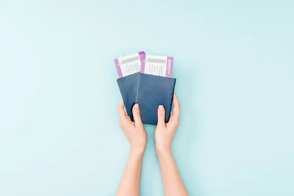Vista recortada de la mujer con pasaportes y billetes de avión sobre fondo azul - foto de stock