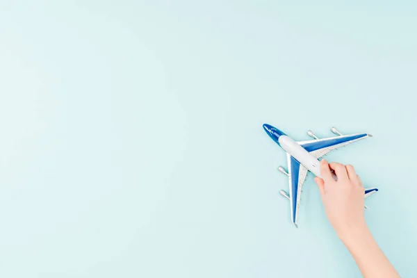 Обрезанный вид женщины, держащей игрушечный самолет на синем фоне — стоковое фото