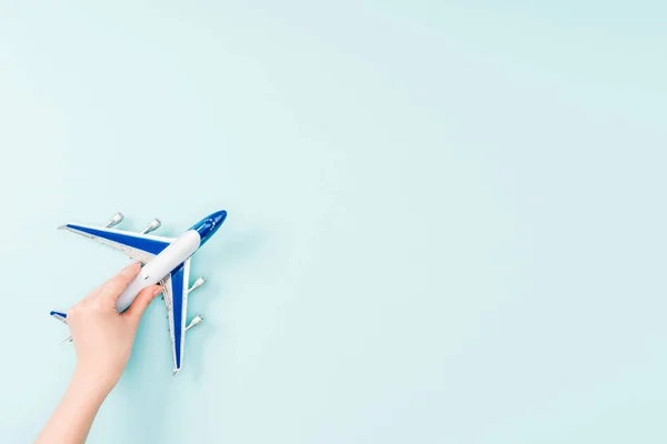 Vue recadrée de la femme tenant petit avion jouet sur fond bleu — Photo de stock