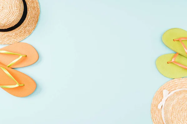 Vue de dessus des chapeaux de paille et des tongs sur fond bleu — Photo de stock