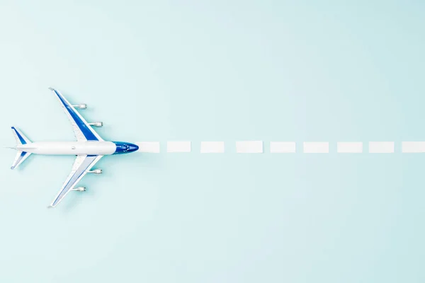 Top view of toy plane and dotted line on blue background — Stock Photo