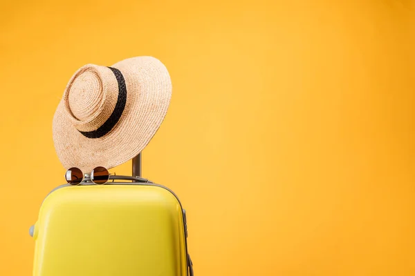 Сумка для подорожей, солом'яний капелюх і сонцезахисні окуляри ізольовані на жовтому — стокове фото