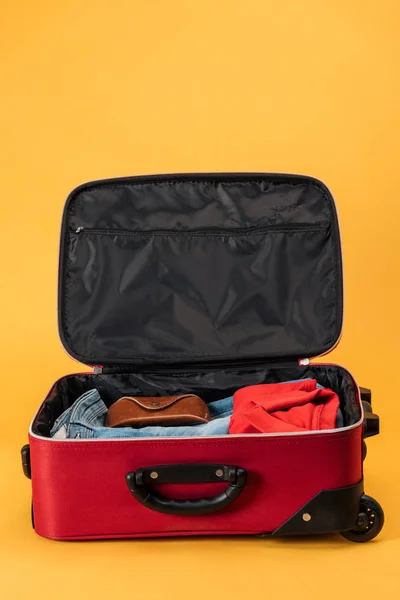 Caso e roupas em saco de viagem no fundo amarelo — Fotografia de Stock