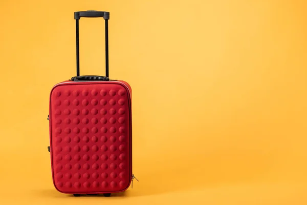 Bolsa de viaje roja con ruedas y asa sobre fondo amarillo - foto de stock
