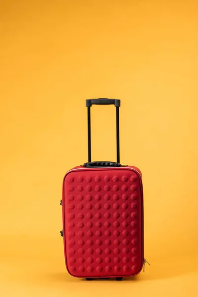 Bolsa de viaje roja con ruedas sobre fondo amarillo - foto de stock