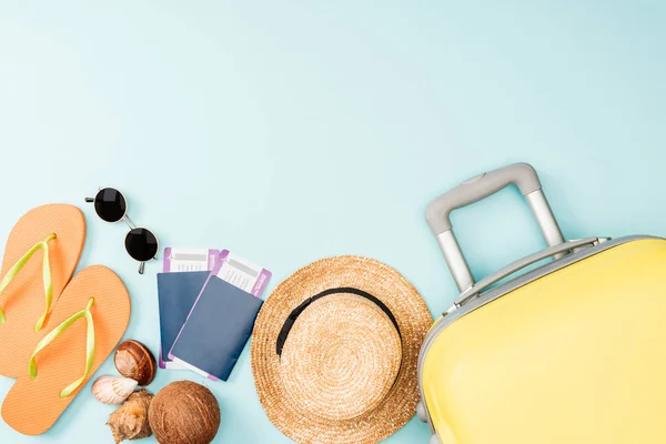 Вид сверху соломенной шляпы, кокоса, шлепанцев, ракушек, солнцезащитных очков, паспортов, авиабилетов и дорожной сумки на синем фоне — стоковое фото