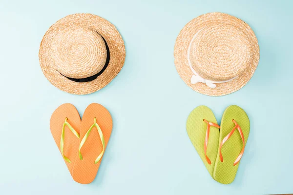 Vue de dessus des chapeaux de paille et des tongs sur fond bleu — Photo de stock