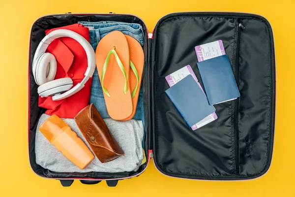 Vista superior de fones de ouvido palha, passaportes e passagens aéreas em saco de viagem isolado em amarelo — Fotografia de Stock