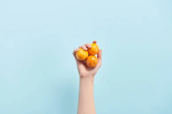 Vista cortada da mulher segurando tangerinas laranja na mão isolado em azul — Fotografia de Stock