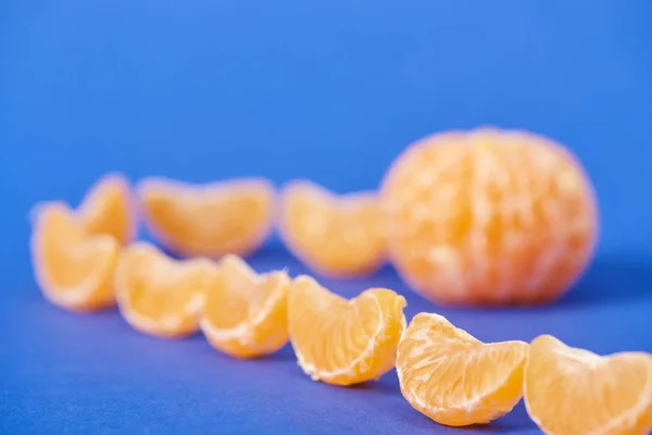 Selective focus of tasty peeled tangerine slices on blue background — Stock Photo
