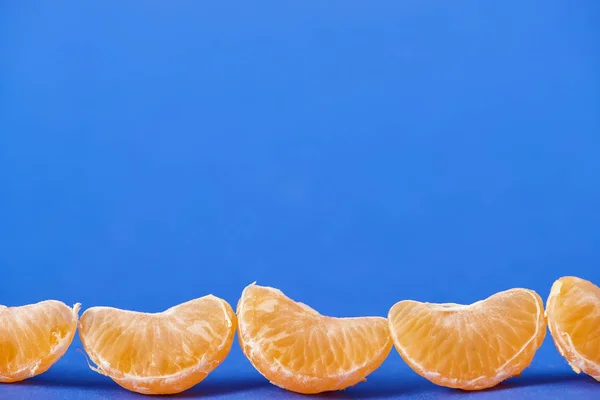 Leckere geschälte Mandarinenscheiben isoliert auf blauem Hintergrund — Stockfoto