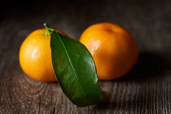 Selective focus of green leaf on organic tasty tangerine on wooden table — Stock Photo