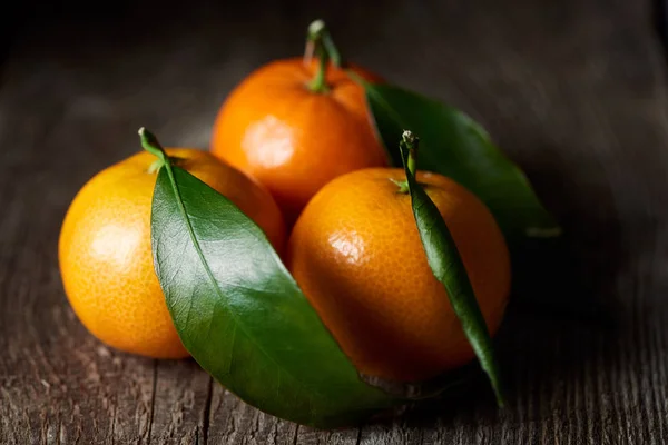 Selective focus of organic tasty tangerines with green leaves on wooden table — Stock Photo