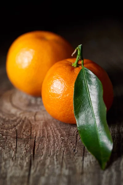 Selective focus of green leaf on tasty tangerine on wooden table — Stock Photo
