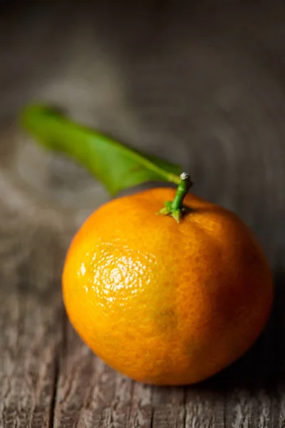 Fuoco selettivo di mandarino saporito con foglia verde su tavolo di legno — Foto stock