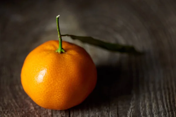 Selective focus of fresh tangerine with green leaf on wooden table — Stock Photo