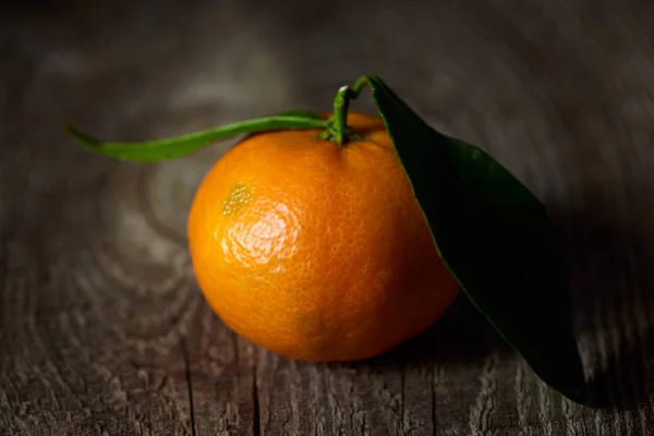 Enfoque selectivo de mandarina orgánica con hojas verdes en la mesa de madera - foto de stock