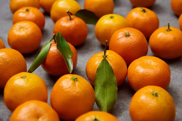 Selective focus of orange tangerines with green leaves on grey table — Stock Photo