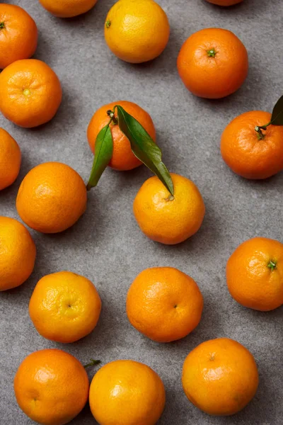 Sweet organic tangerines with green leaves on grey table — Stock Photo