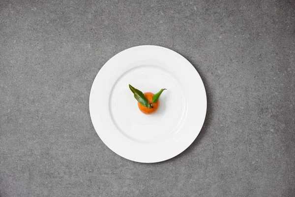 Vista dall'alto di mandarino dolce biologico con foglie verdi su piatto bianco — Foto stock