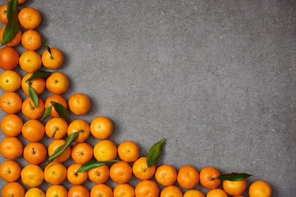 Top view of organic tangerines with green leaves on grey table — Stock Photo