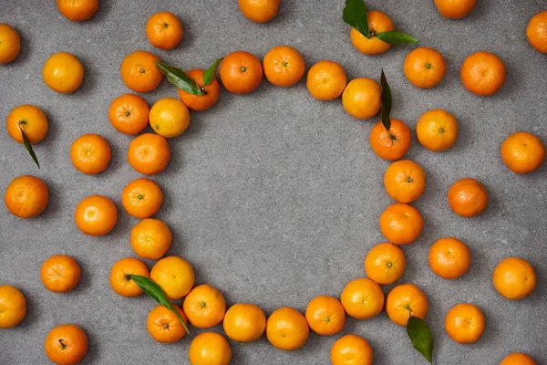 Vista superior de tangerinas doces com folhas verdes na mesa cinza — Fotografia de Stock