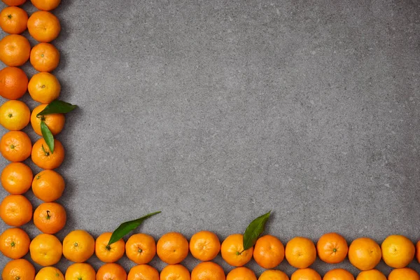 Top view of ripe organic tangerines with green leaves on grey table — Stock Photo