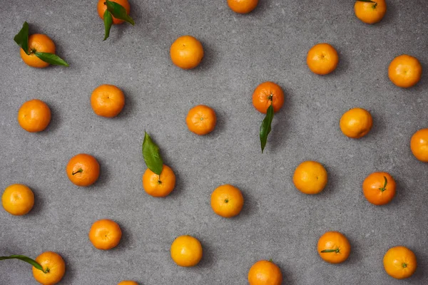 Flat lay of sweet tangerines with green leaves on grey table — Stock Photo