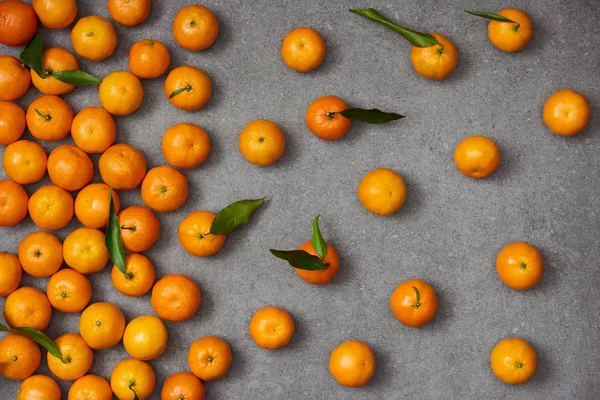 Top view of sweet orange tangerines with green leaves on grey table — Stock Photo
